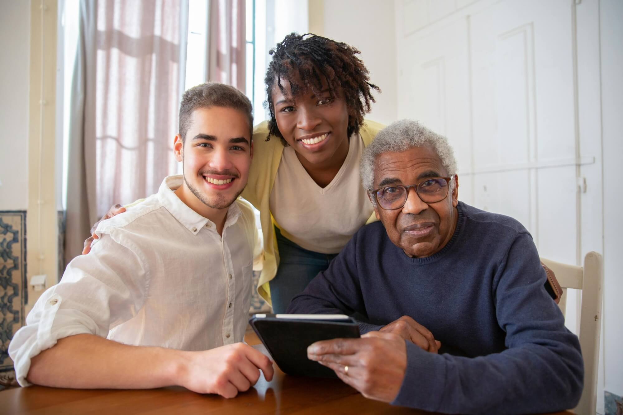 Three family members smiling together with a tablet