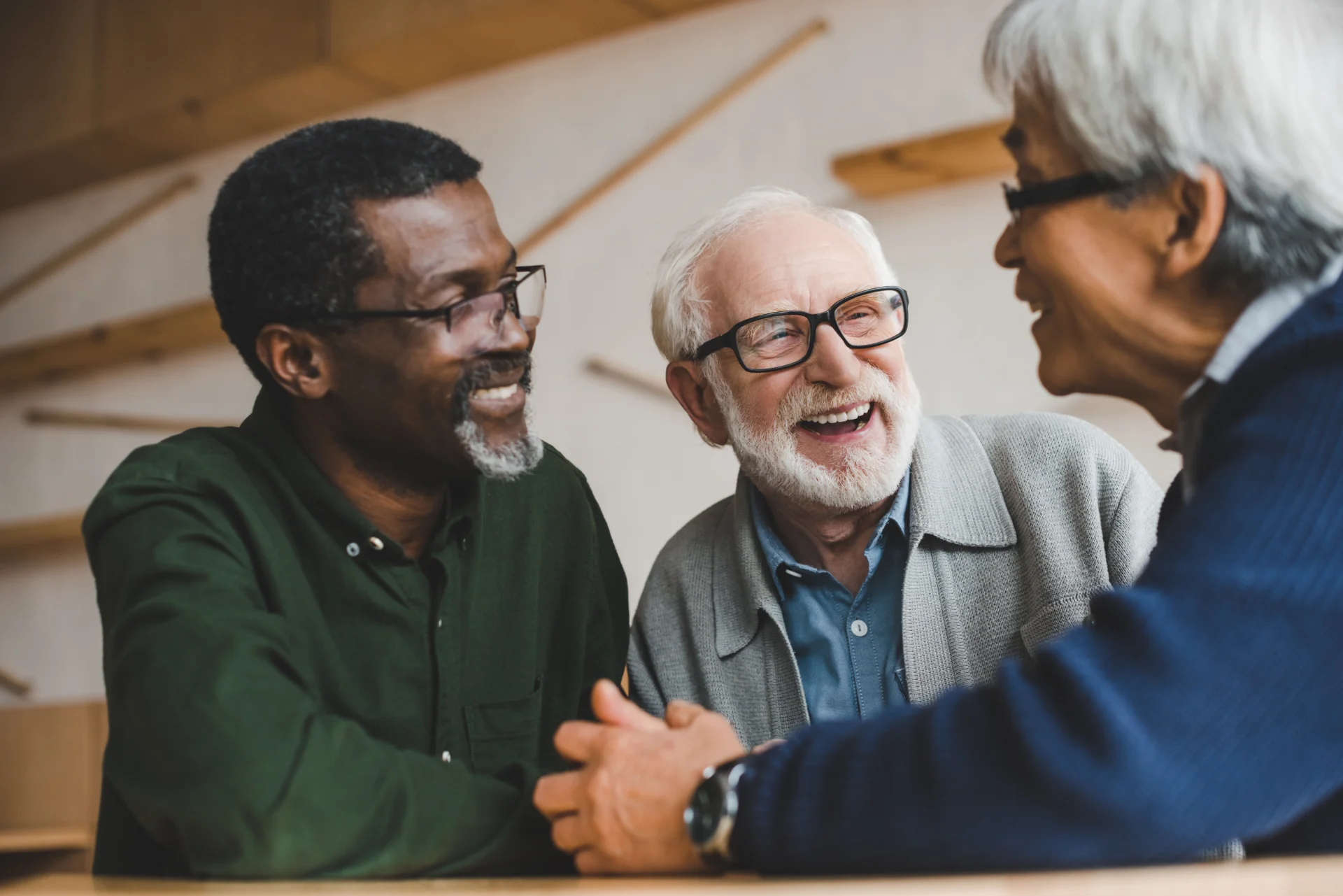 Three older men laughing together at a table